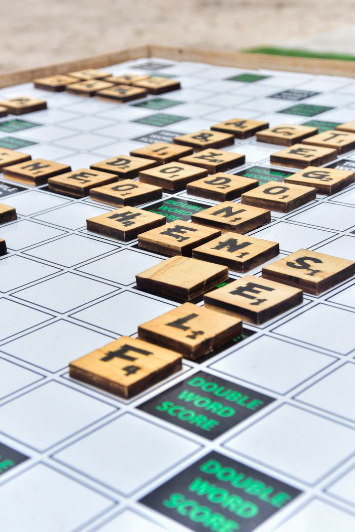 Wooden Scrabble tiles on a game board, showcasing words and scores.