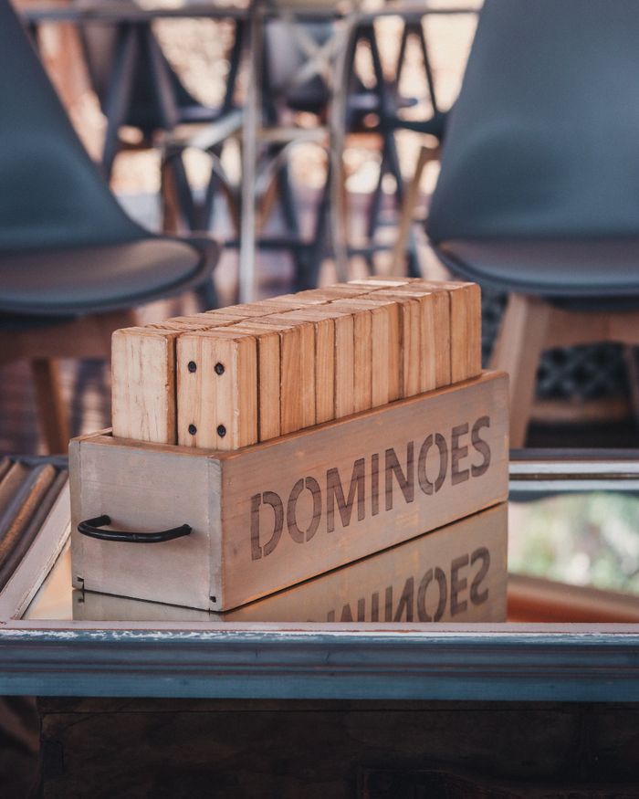 A rustic wooden box of dominoes reflected on a glass table indoors, creating a cozy atmosphere.